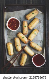 Top View Of Egg Rolls In Sweet And Sour Sauce Over A Dark Rustic Table With Chop Sticks. Garnished With Green Onions. Overhead Table Top View. 