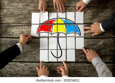 Top view of eight male hands assembling a colourful umbrella with cards over textured rustic desk. Conceptual of safety, shelter and insurance. - Powered by Shutterstock