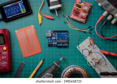 Top view of electronic lab bench showing an Arduino UNO microcontroller surrounded by basic electronics tinkering tools