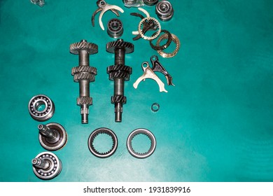 Top View Of The Elements Of The Manual Transmission That Lie On The Green Floor In The Auto Repair Shop