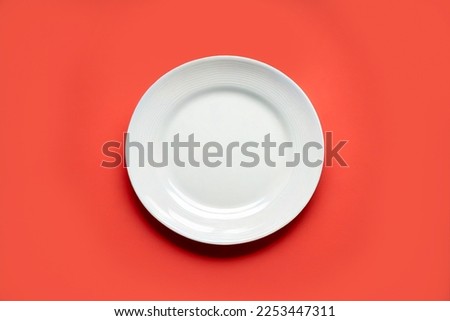 Top view empty blank ceramic round white plate isolated on pastel red background with clipping path.