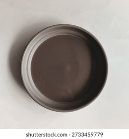 Top view of an empty brown ceramic bowl placed on a clean white background