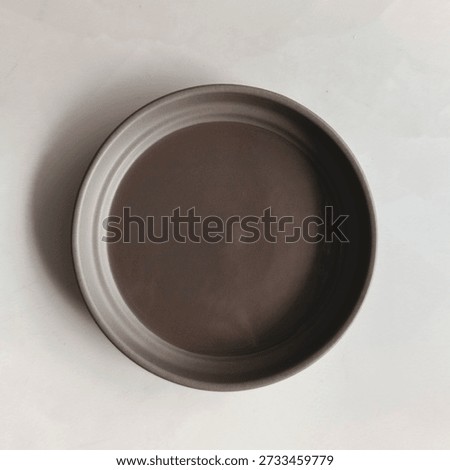 Top view of an empty brown ceramic bowl placed on a clean white background