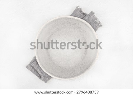 Top view of empty ceramic plate on linen napkin over light textured background. Minimal dining mockup with copy space.