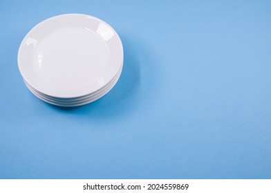 A top view of  empty ceramic white plates on a blue  background