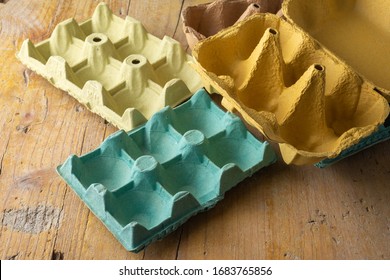 Top view of empty egg cartons, of various colors, to recycle, on rustic wooden board, horizontal - Powered by Shutterstock