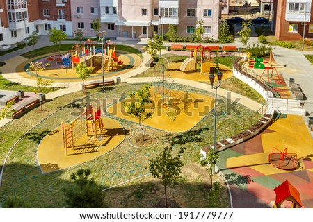 Top view of empty new modern children playground in courtyard of high-rise residential buildings in sunny summer day.