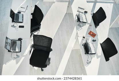 Top view, empty office interior and table with laptops in coworking space in creative startup company. Above, desk and computer in room with furniture, chairs or modern design for business technology