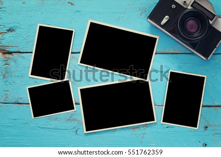 Top view of empty photo frames next to old camera over wooden table. Ready to put photographs