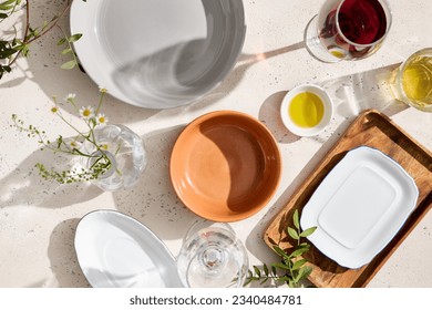 Top view of empty plates, clear glasses with prominent shadows on a textured white table with bright sunlight. Perfect for food or product design and advertising. - Shutterstock ID 2340484781