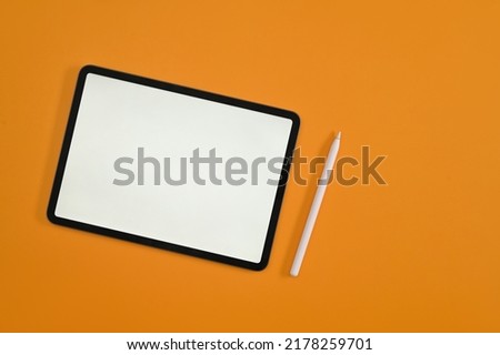 Top view with empty screen of digital tablet, tablet and stylus pen on yellow studio background.