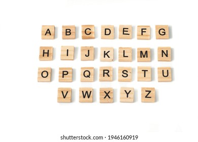 Top view of english alphabet made of square wooden tiles with the English alphabet scattered on a white background with space for text. The concept of thinking development, grammar.