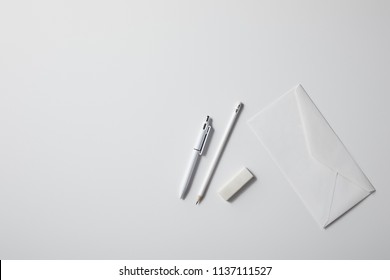Top View Of Envelope With Pen And Pencil On White Surface For Mockup