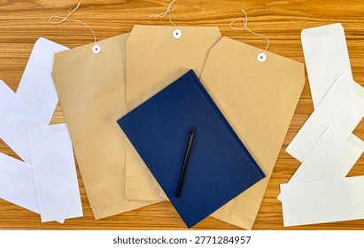 Top view of envelopes, notebook and papers on wooden desk. Clean composition representing business communication, documentation, office work and organization