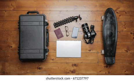 Top view of equipment for vlogging. Camera, laptop, tripod, smartphone, passport, spectacles, suitcase and skateboard 