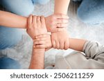 Top view of family hands holding each others wrists in circle, creating chain of support or unity. Four members of family linked in lock. Concept of connection, teamwork, family, strength, trust.