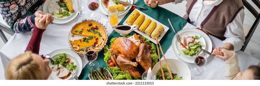 Top View Of Family Holding Hands And Praying Near Delicious Thanksgiving Dinner, Banner