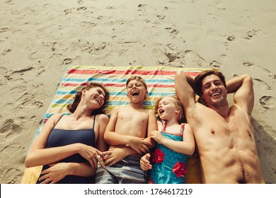 Top View Of Family Lying On The Beach. Happy Mother And Father With Two Children Relaxing On Beach On Summer Holiday.