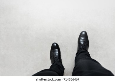 Top View Feet Of Businessman In Black Shoes Walking On Grey Road. Walking Go To Dream Concept.