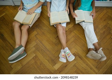 Top View Of Feet Of Children Reading Books On Floor