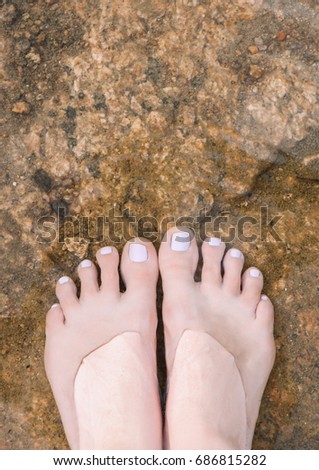 Top view of female feet under clear water.