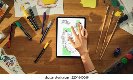 Top View Of Female Footwear Designer Drawing Sketch of Sneakers on Tablet Computer from Upcoming Collection. Talented Woman Designing With Finder on Display. Shoe Design Process Concept. - Powered by Shutterstock