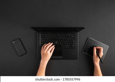 Top View Of Female Graphic Designer Or Retoucher Hands Working On Laptop And Digital Tablet. Dark Black Desk Flat Lay.