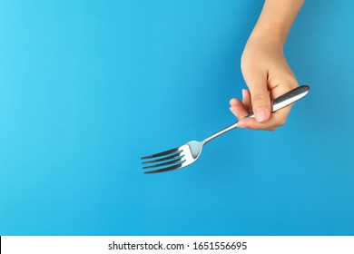 Top View Female Hand Holding A Fork On Blue Background