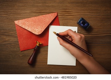 Top view of female hand writing a letter on the wooden desk.