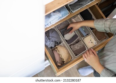 Top view female hands comfortable boxes storage for panties, socks, bras Konmari method storage. Woman neatly putting underwear into organizer container for vertical system cupboard general cleaning