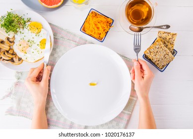 Top View Female Hands Holding Knife And Fork And White Plate With Vitamin Pill On The Served Wooden Table With Breakfast Meal. Pill Instead Of Food. Healthy Diet Concept. Selective Focus