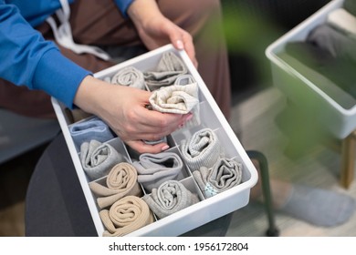 Top view female hands holding organizer drawer divider with socks storage Marie Kondo's method. Housewife arms arranging placing wardrobe cupboard. Modern woman use container for folded clothes