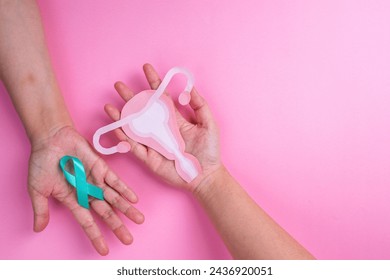 Top View of Female Hands Holding Teal Ribbon and Uterus Cutout. Ovarian cancer and Gynecological Disorders Concept. - Powered by Shutterstock