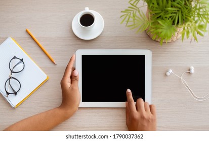 Top view of female hands using tablet with black blank screen, working at office, mock up, copyspace