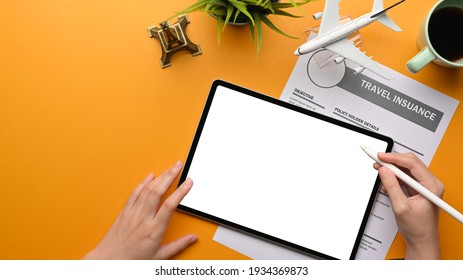 Top view of female hands using with digital tablet to plan her travel trip and filling travel insurance form, clipping path, travel concept - Powered by Shutterstock