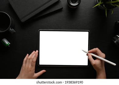 Top view of female hands using digital tablet with stylus pen on dark workspace, clipping path
