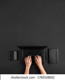 Top View Of Female Hands Working On Black Laptop. Dark Minimal Ofice Desk Flat Lay. Copy Space.