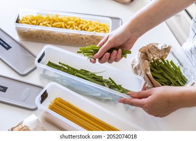 Top view female housewife placing sorting different kinds of vegan pasta into pp boxes. Woman storage organizing keeping products on modern kitchen table. General cleaning, tidying up at cuisine