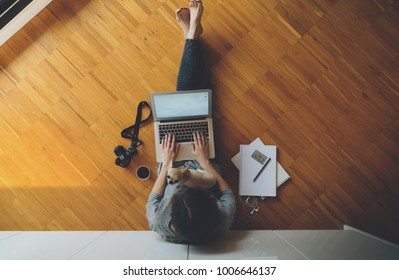 Top View Of A Female Student Relaxes Sitting On A Wooden Floor At Home And Chooses Suitable Online Courses. Young Businesswoman Typing Text Message On Laptop Keyboard. Vintage Camera, Credit Card