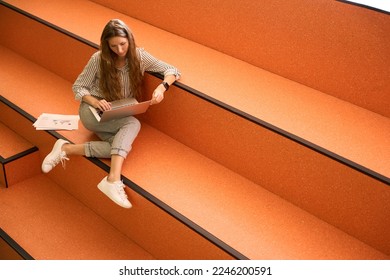 Top view of female student using laptop while sitting on steps - Shutterstock ID 2246200591