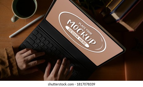 Top view of female using mock up digital tablet with keyboard and stylus pen on study table