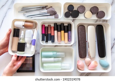 Top View Of Female Visagiste Is Neatly Placing Cosmetic And Vanity Items In MUJI's PP Makeup Storage Boxes With Various Sizes On White Marble Dressing Table. Decluttering And Organization Concept.