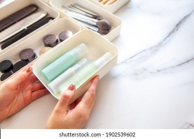 Top View Of Female Visagiste Is Neatly Placing Cosmetic And Vanity Items In MUJI's PP Makeup Storage Boxes With Various Sizes On White Marble Dressing Table. Decluttering And Organization Concept.