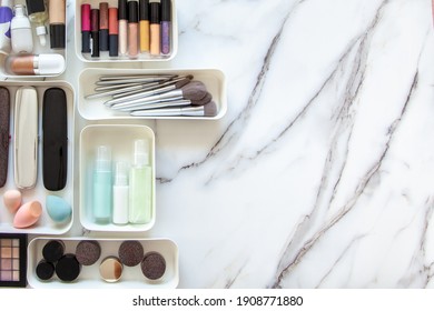 Top View Of Female Visagiste Is Neatly Placing Cosmetic And Vanity Items In MUJI's PP Makeup Storage Boxes With Various Sizes On White Marble Dressing Table. Decluttering And Organization Concept.