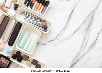 Top View Of Female Visagiste Is Neatly Placing Cosmetic And Vanity Items In MUJI's PP Makeup Storage Boxes With Various Sizes On White Marble Dressing Table. Decluttering And Organization Concept.