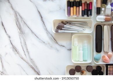 Top View Of Female Visagiste Is Neatly Placing Cosmetic And Vanity Items In MUJI's PP Makeup Storage Boxes With Various Sizes On White Marble Dressing Table. Decluttering And Organization Concept.