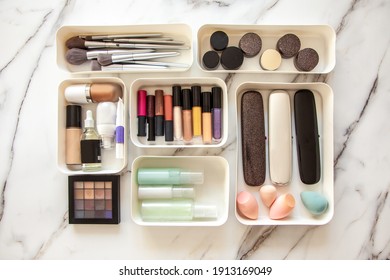 Top View Of Female Visagiste Is Neatly Placing Cosmetic And Vanity Items In MUJI's PP Makeup Storage Boxes With Various Sizes On White Marble Dressing Table. Decluttering And Organization Concept.