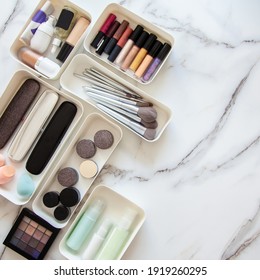 Top View Of Female Visagiste Is Neatly Placing Cosmetic And Vanity Items In MUJI's PP Makeup Storage Boxes With Various Sizes On White Marble Dressing Table. Decluttering And Organization Concept.