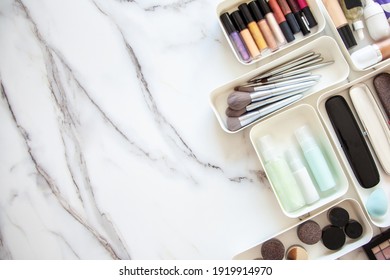 Top View Of Female Visagiste Is Neatly Placing Cosmetic And Vanity Items In MUJI's PP Makeup Storage Boxes With Various Sizes On White Marble Dressing Table. Decluttering And Organization Concept.