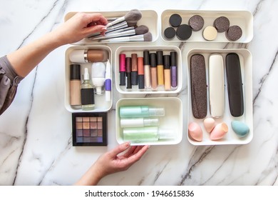 Top View Of Female Visagiste Is Neatly Placing Cosmetic And Vanity Items In MUJI's PP Makeup Storage Boxes With Various Sizes On White Marble Dressing Table. Decluttering And Organization Concept.